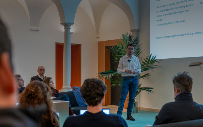 Speaker presenting to an audience at PoW.space Lugano during a seminar on regulatory differences in digital asset laws between Switzerland, the EU, and Dubai.