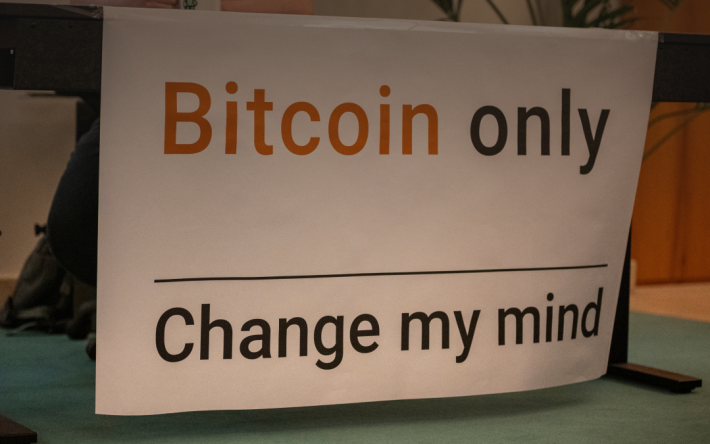 Banner reading ‘Bitcoin only, Change my mind’ displayed at a PoW.space Lugano event, sparking discussion on cryptocurrency and Bitcoin perspectives.